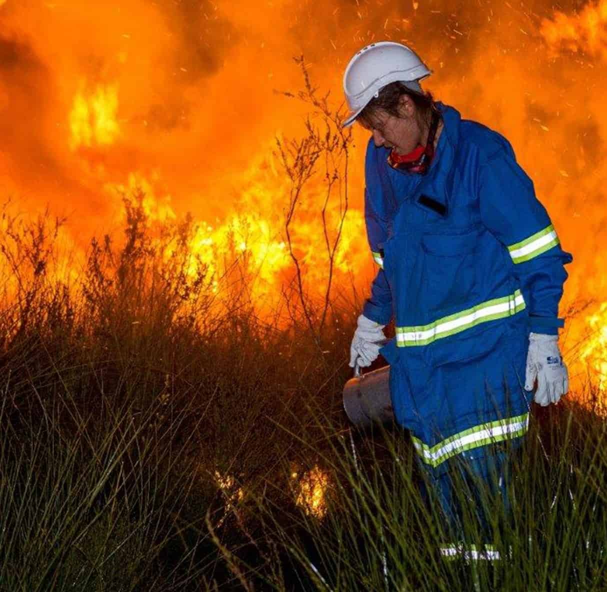 A woman in personal protective equipment practises prescribed burning