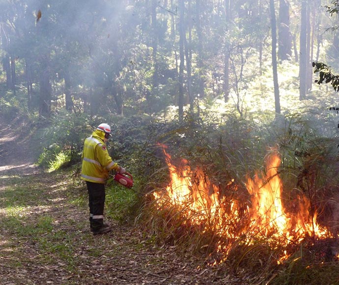 Firefighter lighting up grass along a track.