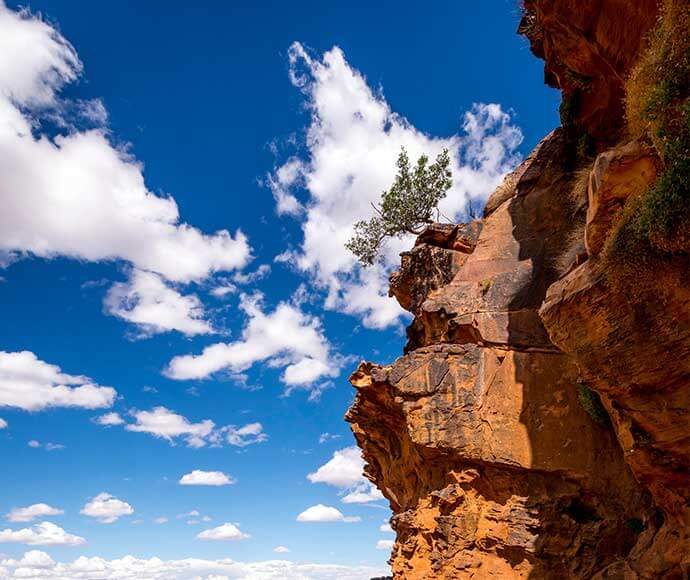 Beautiful orange cliff face with a perfect blue sky and fluffy white clouds