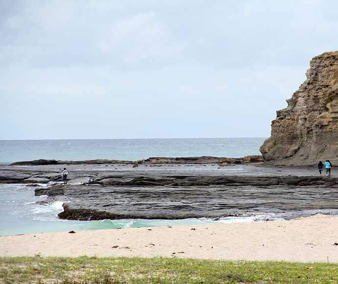 People wandering along rock platforms, inter tidal zones, Depot Beach