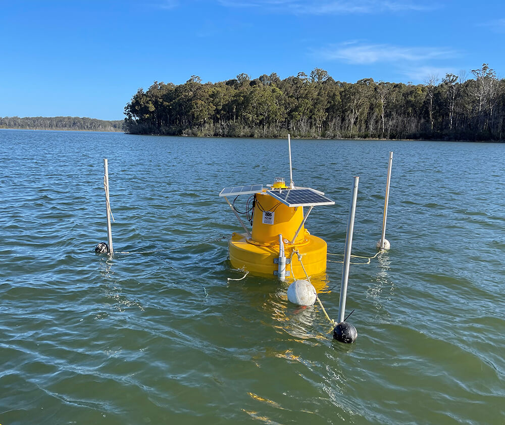 Yellow water quality monitoring buoy floating on water in lake.