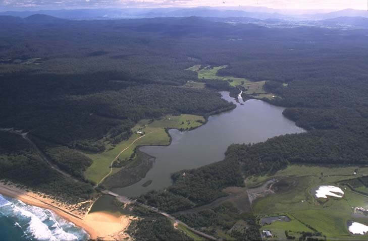 A view of Baragoot Lake with Baragoot Beach in the foreground and Bermaguee Nature Reserve in the background