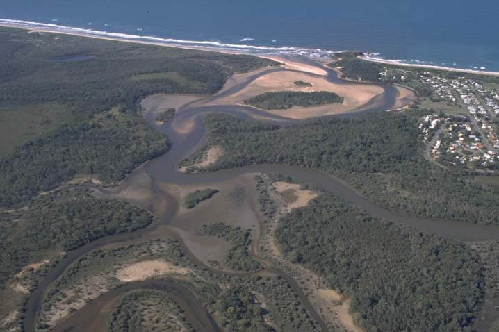 A view of Corindi River meeting the sea next to the town of Red Rock with the beach in the background