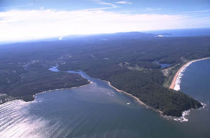 A view of Cullendulla Creek flowing into Batemans Bay with Long Beach in the background