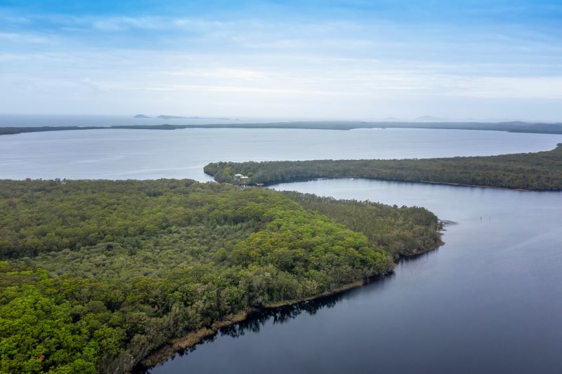 Aerial photograph showing the winding, interconnected lakes of Myall lakes, with a view out to the ocean in the distance