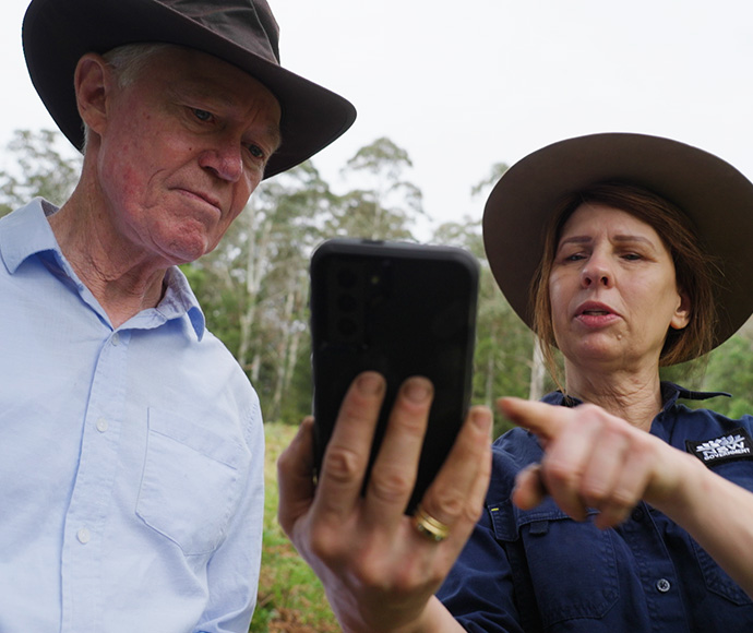 A woman holding up her phone showing a man how to use it