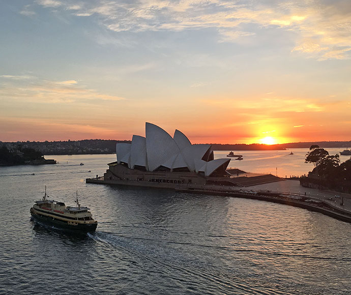 Sunrise over Sydney Opera House with a ferry in the foreground