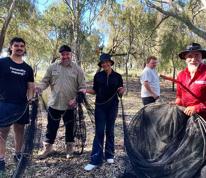 A group of people holding a large black fishing net