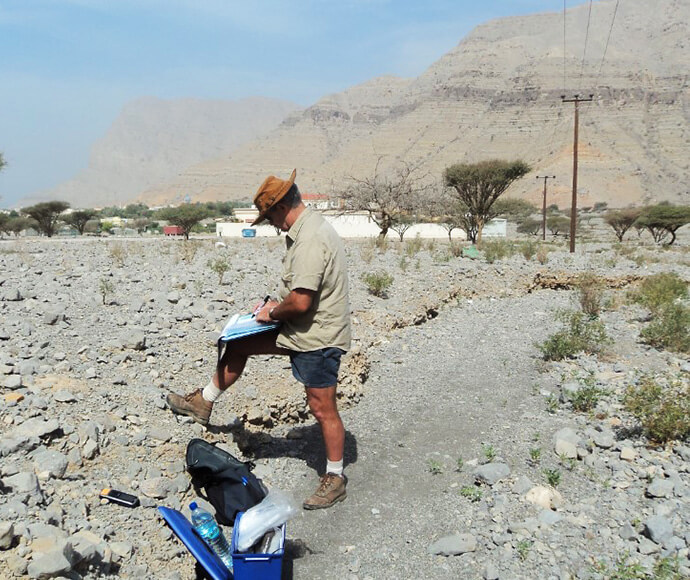 David is standing over rocky soil writing its description in a folder