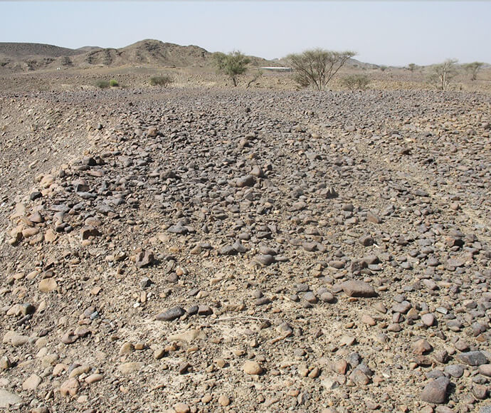 A road paved with loose rocks. There is some red dirt dusting the rocks