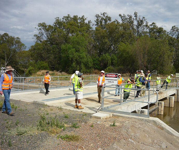 Macquarie-Cudgegong EWAG wearing safety gear while inspecting the Marebone Fishway at Macquarie Marshes. The group is standing on a concrete structure beside a body of water, with a 'DANGER' sign visible, indicating an active work or inspection site.