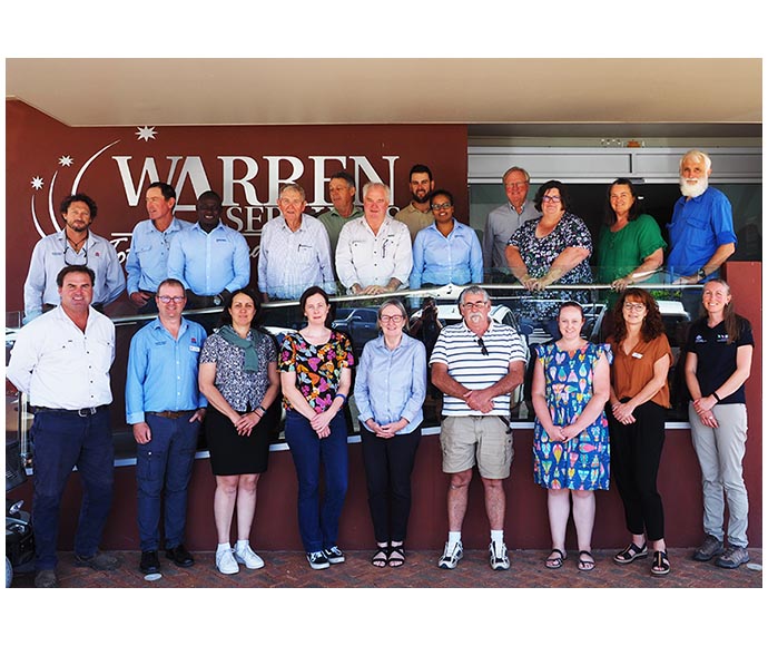 A group of individuals standing in front of a sign that reads ‘WARREN SERVICES,’ with their faces obscured for privacy.