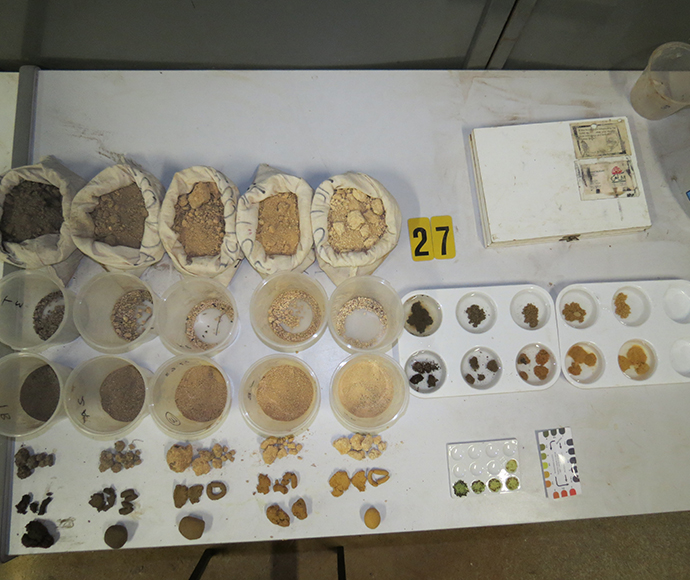 A collection of soils samples sit in white bags on a table top.