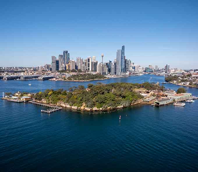 Aerial view of a city skyline near a body of water with boats and greenery in the foreground