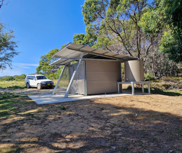 A toilet block in the middle of a clearing in the bush.