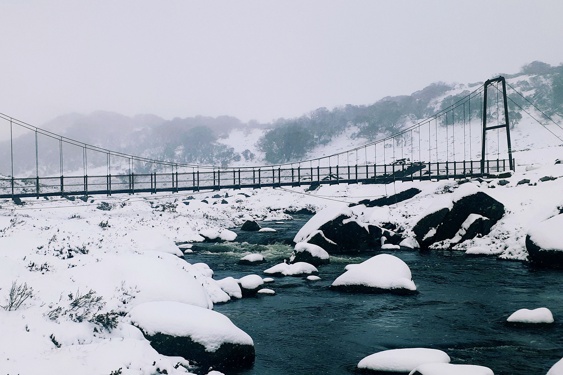 A steel bridge cross a river in a snowy landscape