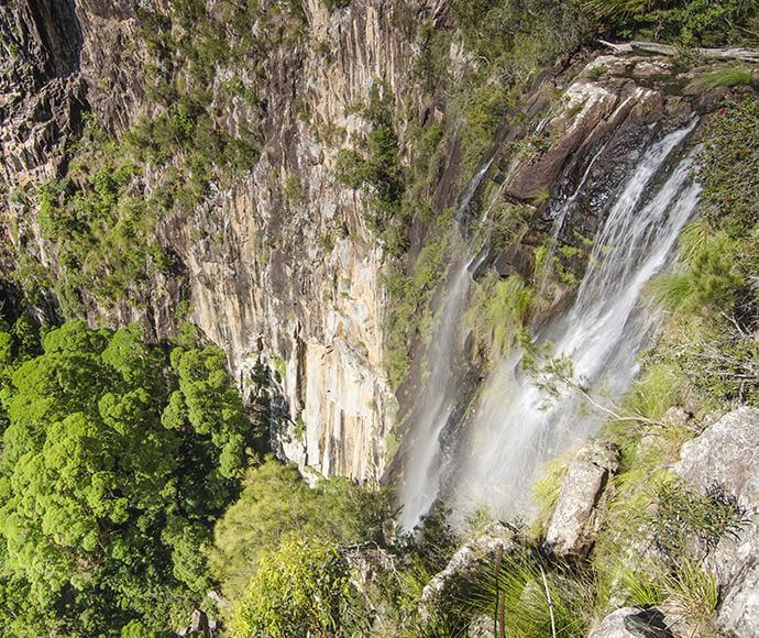 Sure thing! How about this: “Breathtaking Minyon Falls in Nightcap National Park, cascading down sheer cliffs surrounded by dense, lush forest.