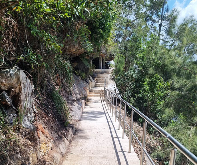 Wattamolla Beach access track, handrail stretches along the length of the track up to a set of stone steps. 