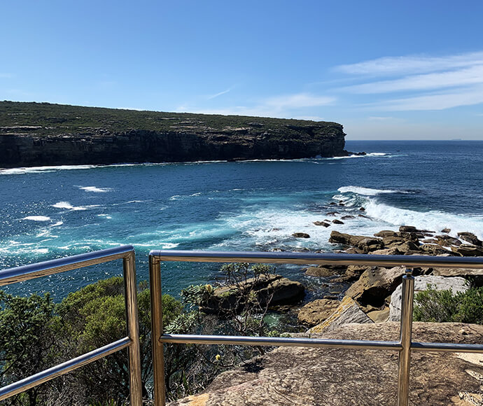 A fenced clifftop lookout with a view out across the bay to a nearby headland.