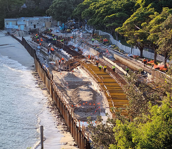 A beachside construction site with workers and equipment engaged in infrastructure development