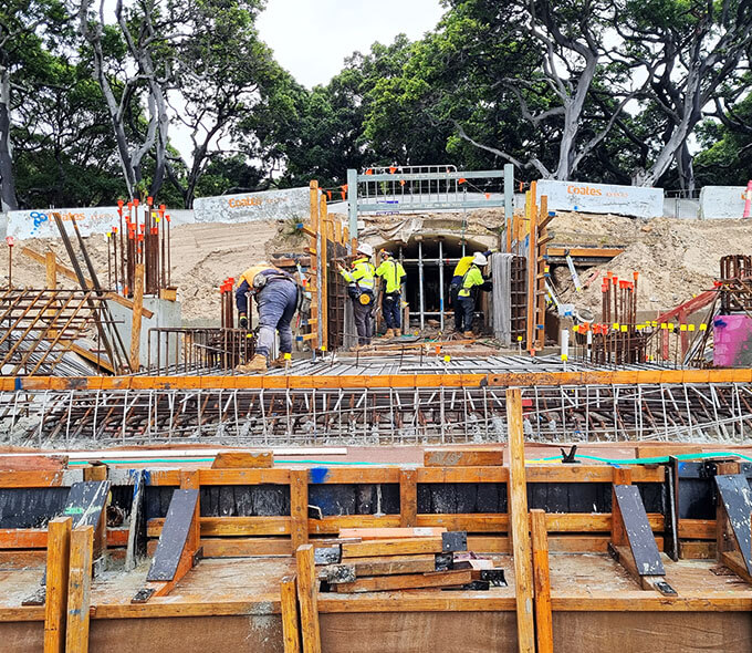 A construction site where workers are engaged in building concrete structures amidst scaffolding and excavation activities