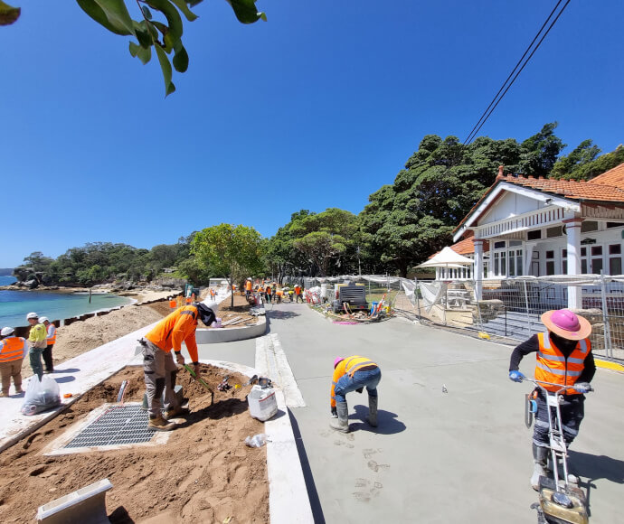 Workers working on and around a freshly laid promenade in a small picturesque bay