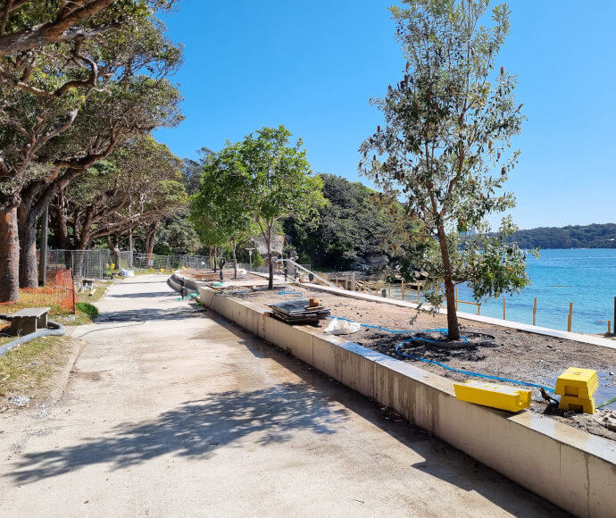 Saplings in a planter box lining a promenade on the shore of a small bay