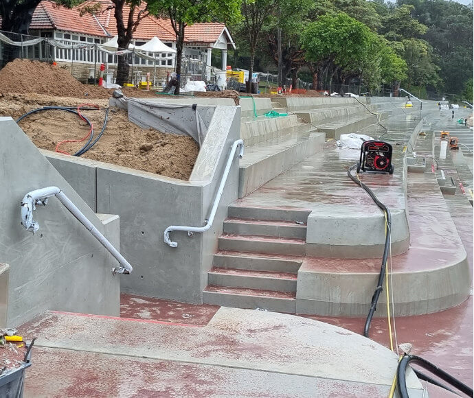 Handrails, stair nosings, construction equipment and steps at the end of concrete bleachers shining wet under the rain