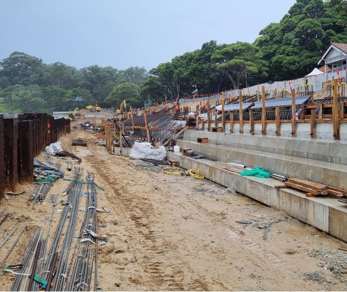 A misty sky and thick treeline overlook construction works on the sand